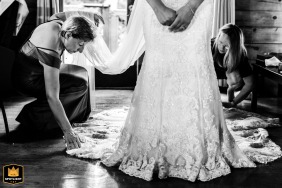 Wedding helpers carefully arrange the bride's dress at a rented house in Plymouth, Massachusetts.